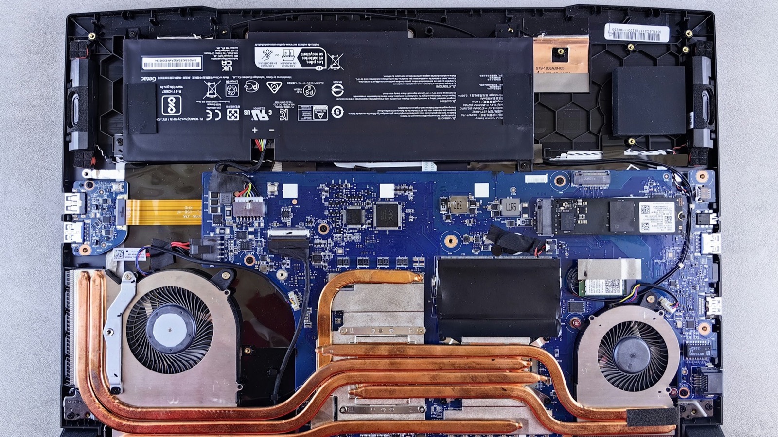 Laptop opened from the underside showing the cooling fans, heat pipes, SSD, RAM and battery